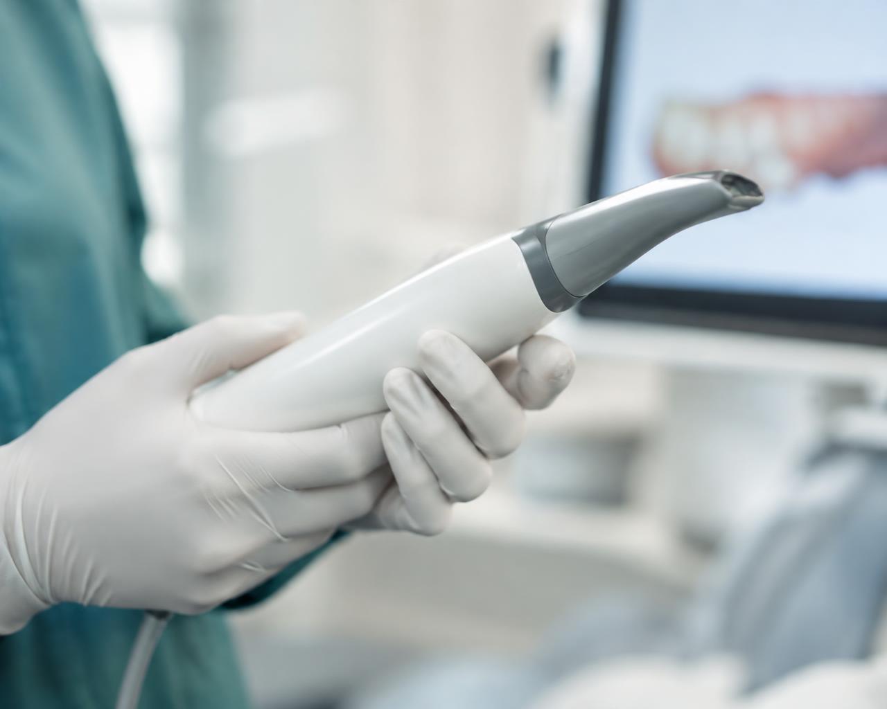 Behandschuhte Hände mit Intraoral-Scanner